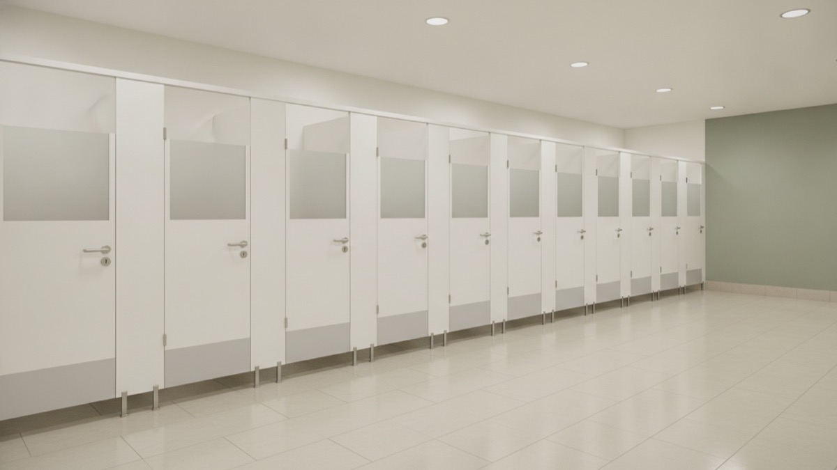 A tidy row of modern commercial washroom cubicles with a subtle green feature wall